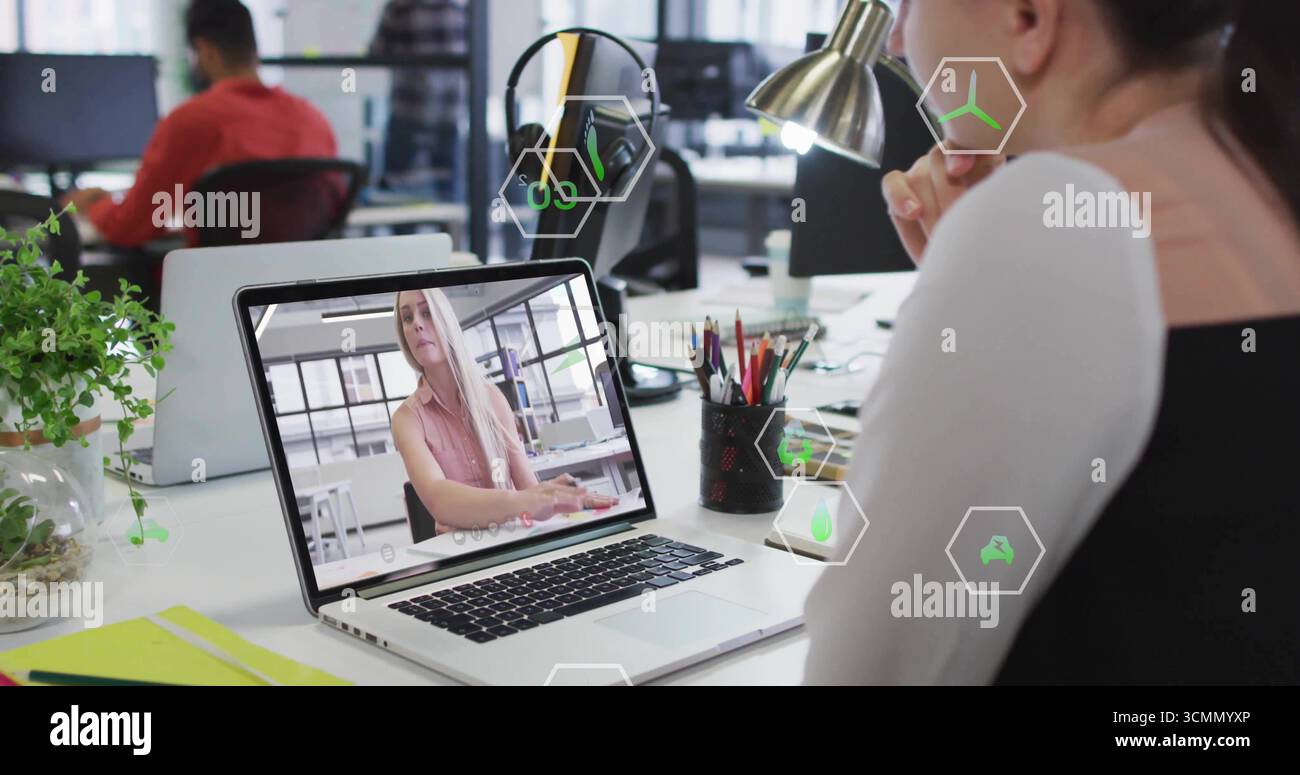Sitzende Frau, die Online-Meetings am offenen Büroschreibtisch mit Laptop, Lampe, Kopierraum durchführt Stockfoto