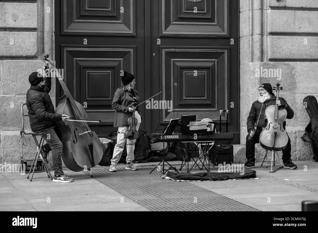 Madrid, Spanien - 19. FEBRUAR 2022: Straßenmusiker mit Doppelzelloes und einer Geige in der Calle de Alcala, Madrid. Stockfoto