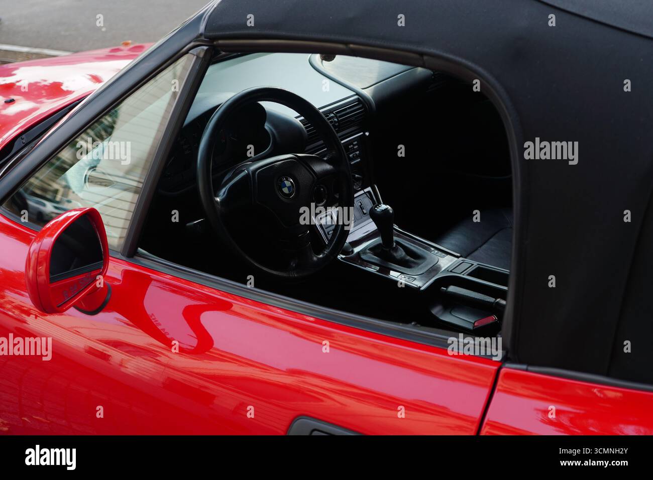 Bukarest, Rumänien – 7. September 2025: Nahaufnahme des Lenkrads und des Innenraums des roten BMW Z3 Roadsters durch offenes Fenster Stockfoto