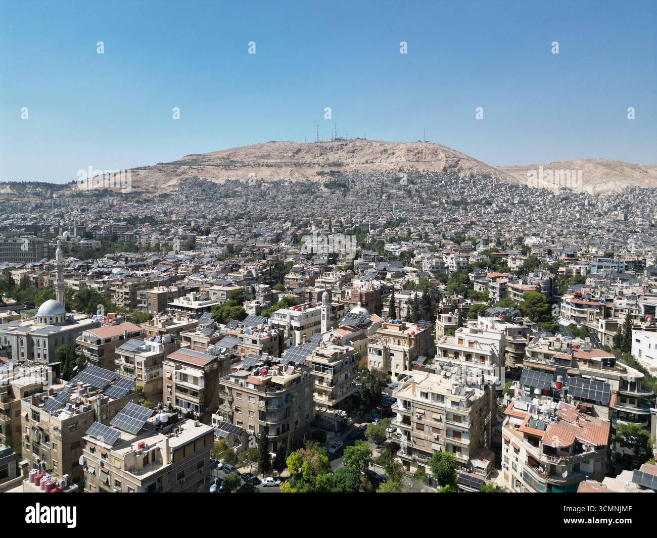 Aus der Vogelperspektive von Damaskus mit Nationalflagge aus der Vogelperspektive zeigt die neue syrische Nationalflagge, die auf einem massiven Pol im Herzen von Damaskus fliegt, mit dem Berg Qasioun, einer der berühmtesten Wahrzeichen der Stadt, die im Hintergrund zu sehen ist. Damaskus Syrien Copyright: XMohammadxBashirxAldaherx Stockfoto