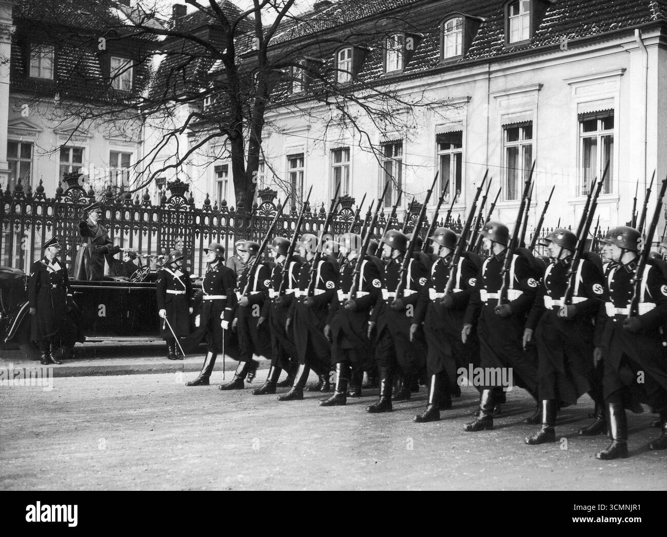 Reichskanzler Adolf Hitler sieht eine Militärparade von seinem Auto aus. Reichsführer-SS Heinrich Himmler steht auf dem Bürgersteig – 1937 Stockfoto