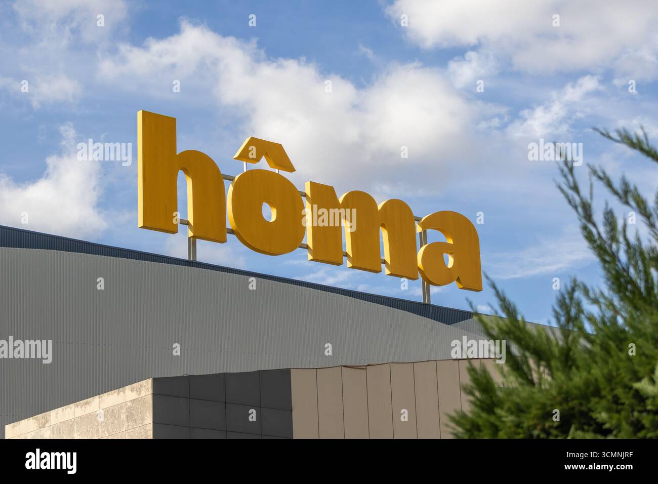 Großes gelbes Logo des Möbelgeschäfts homa, oben auf dem Lagerhaus, strahlend unter einem wunderschönen blauen Himmel Stockfoto