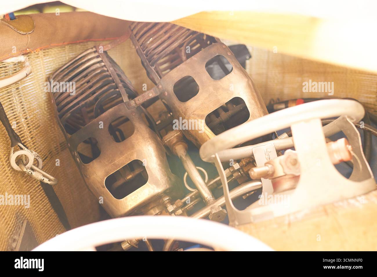 Nahaufnahme mit Komponenten des klassischen Zweizylindermotors im klassischen Fahrzeug, wobei freiliegende Metallteile und mechanische Details hervorgehoben werden, das Lenkrad teilweise im Vordergrund sichtbar ist Stockfoto
