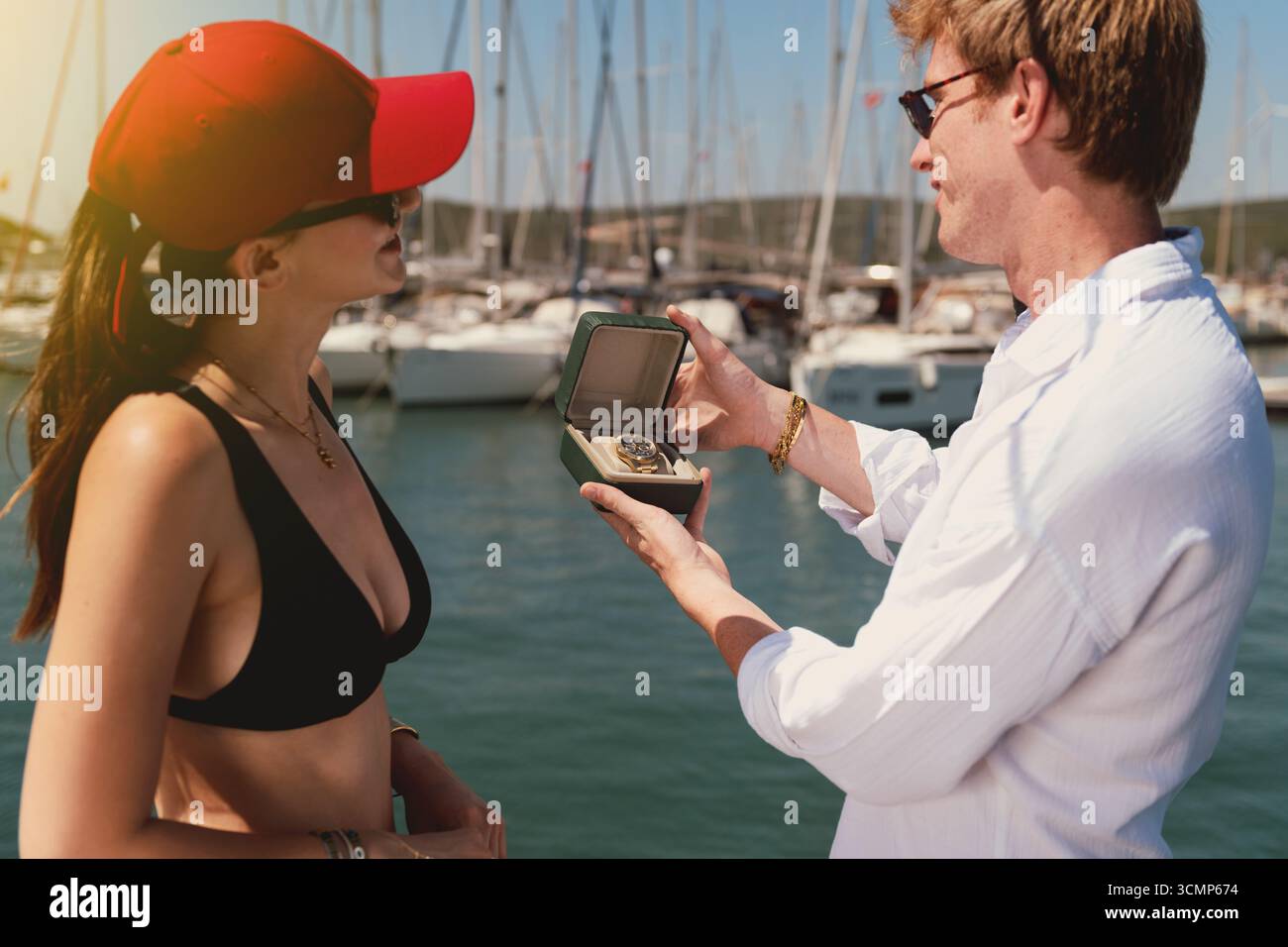 Mann untersucht teure Uhr in Box, während er mit Frau auf dem luxuriösen Yachtdeck steht. Stockfoto