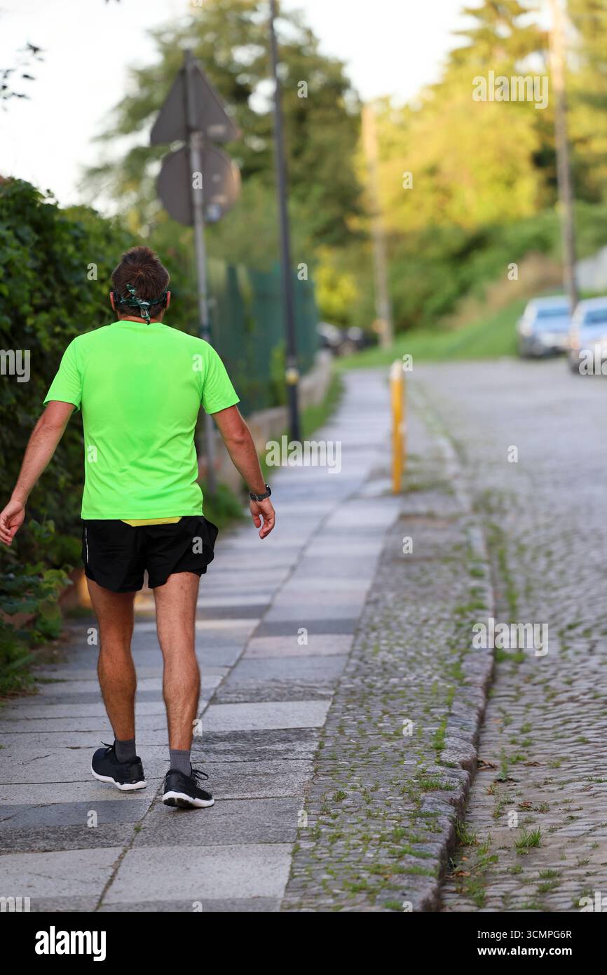 Ein Mann im Runner-Outfit, der den Bürgersteig hinuntergeht Stockfoto