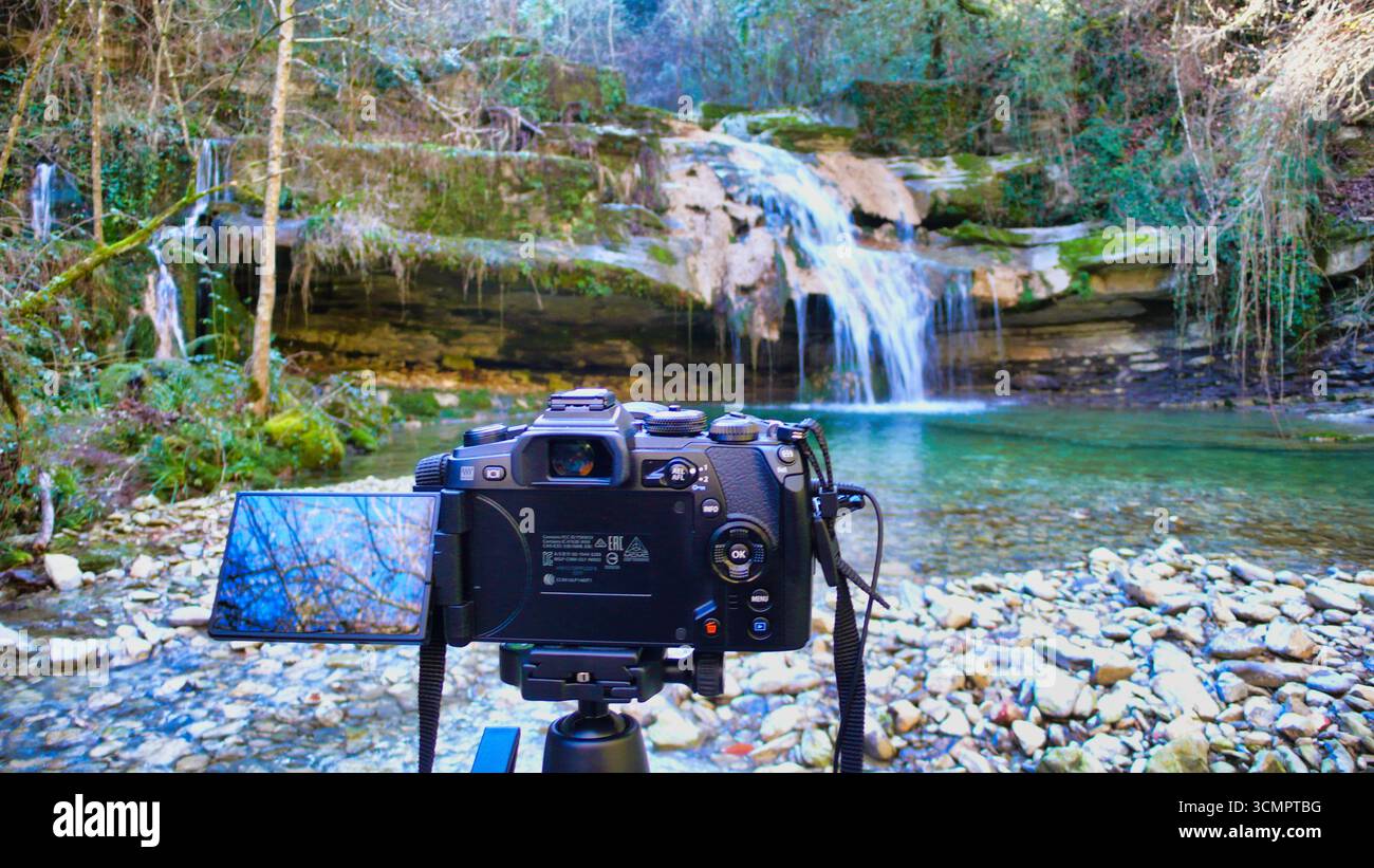 Kameraeinrichtung für den Außenbereich für die Naturfotografie – Eine Digitalkamera auf einem Stativ ist so eingerichtet, dass sie eine lange Belichtung eines Wasserfalls und eines Flusses in einem Wald aufnimmt. Stockfoto