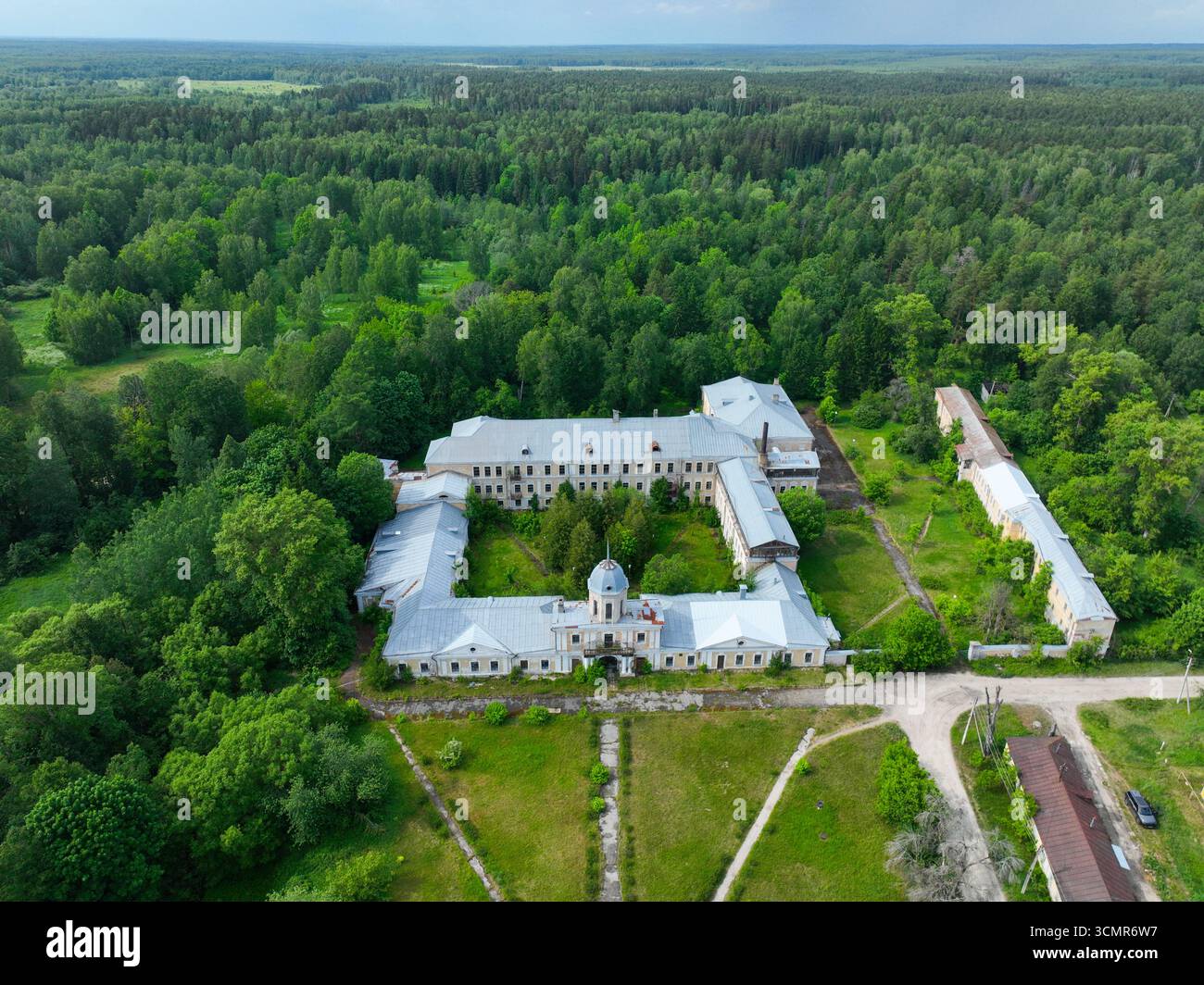 Eine weite Luftaufnahme des verlassenen Sanatoriumskomplexes Andreevskoe, die seine symmetrische Grundrisse mit einem zentralen Innenhof zeigt und von dickem Grau umgeben ist Stockfoto