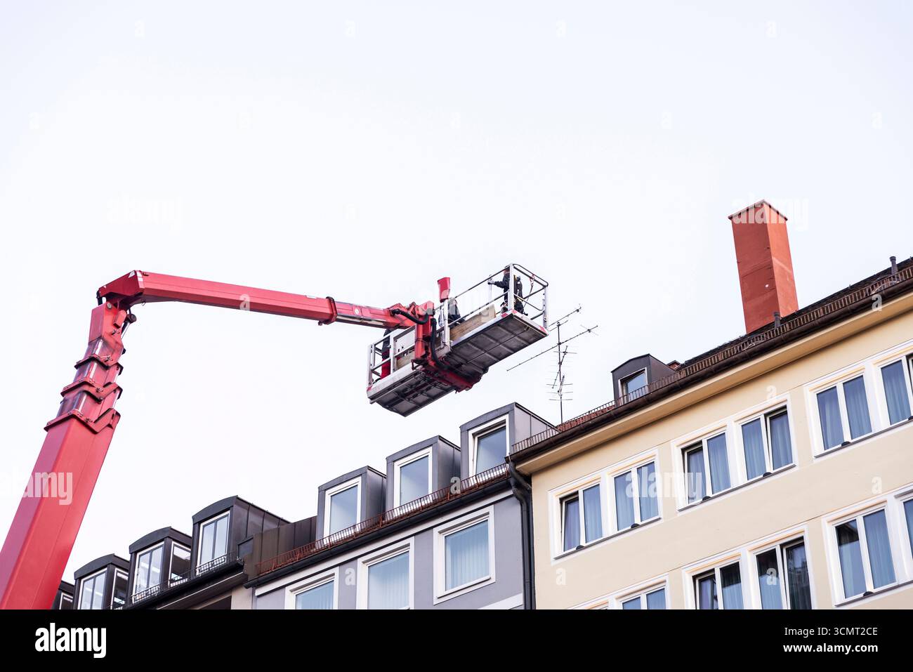 Plattformwagen mit zwei Arbeitern, die ein Dach eines Gebäudes in München, Bayern, Deutschland, befestigen Stockfoto