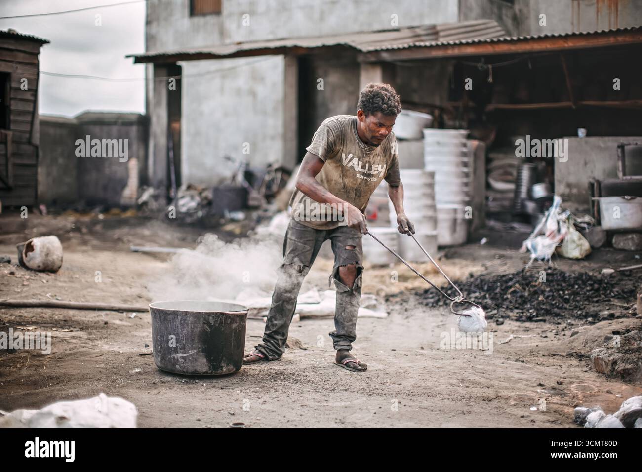 Ambatolampy, Madagaskar - 25. April 2019: Aluminiumverarbeitungsfabrik, Dosen schmelzen in Töpfen über Feuer draußen, Dampf oben, unbekannter Arbeiter h Stockfoto
