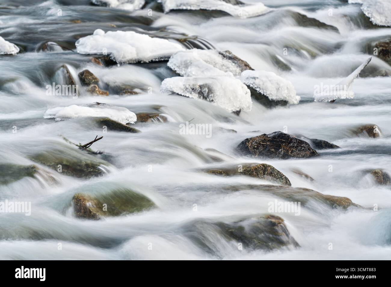 Winter Fluss fließt über Schnee und eisbedeckte Steine, Nahaufnahme, Langzeitfoto Stockfoto