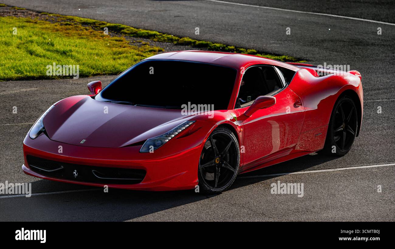 Roter Ferrari 458 Italia Sportwagen auf Asphaltstraße mit schwarzen Leichtmetallfelgen und getönten Fenstern, aus flacher Perspektive fotografiert. Stockfoto Roter Ferrari 458 Italia Sportwagen auf Asphaltstraße mit schwarzen Leichtmetallfelgen und getönten Fenstern, aus flacher Perspektive fotografiert. Stockfoto
