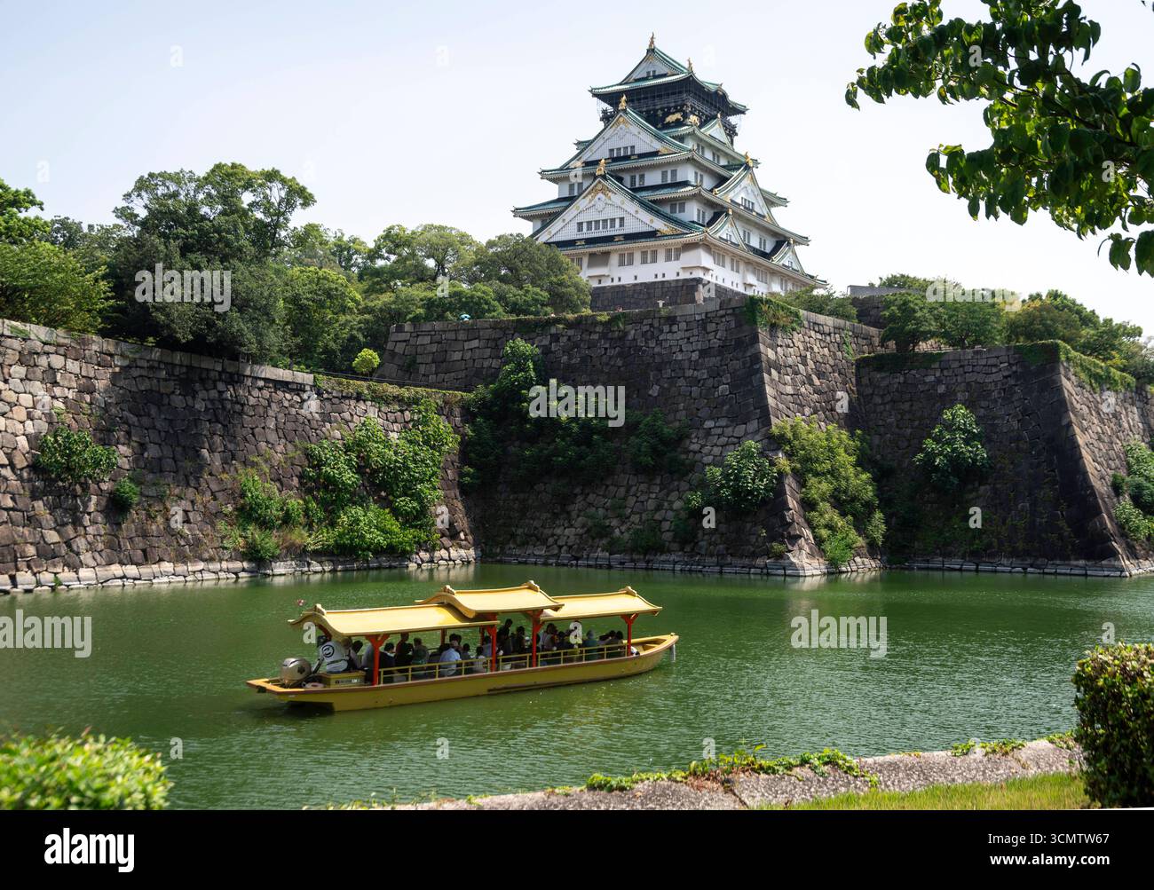 Osaka: Burg in der Stadt. - Ein Ausflugsboot mit Besuchern fährt auf dem Wassergraben um das Osaka Castle. Die Burg inmitten der Millionenstadt war Stockfoto