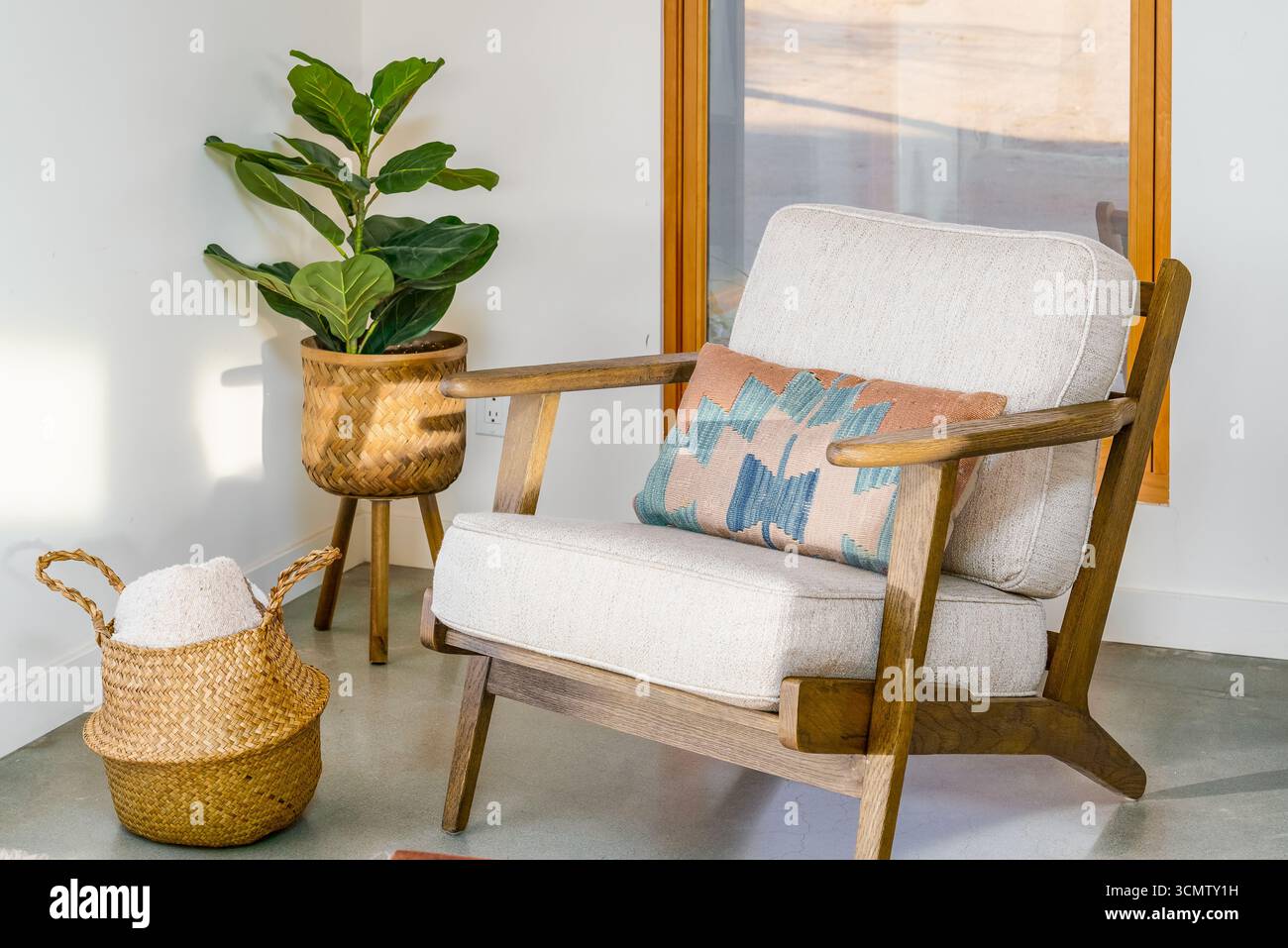 Moderner Loungesessel mit Akzent, Holzrahmen mit südwestlicher Kissenpflanze und gewebtem Korbfenster in der Wohnzimmerecke des Wüstenheims Stockfoto