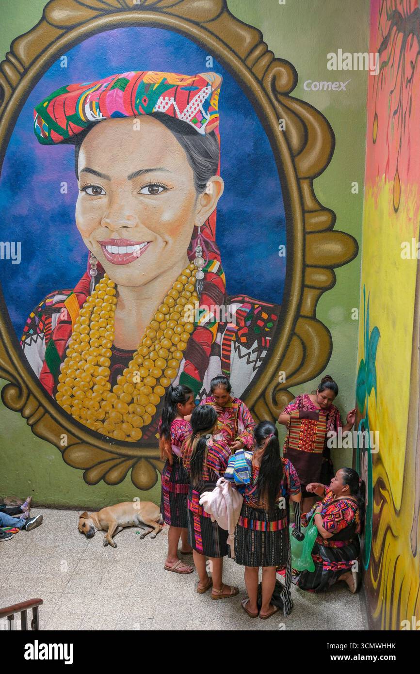 Chichicastenango, Guatemala - 3. Juli 2025: Frauen neben einem Wandgemälde des Künstlers Edwin Gonzalez auf dem Santo Tomas Markt in Chichicastenango, Guatemala. Stockfoto