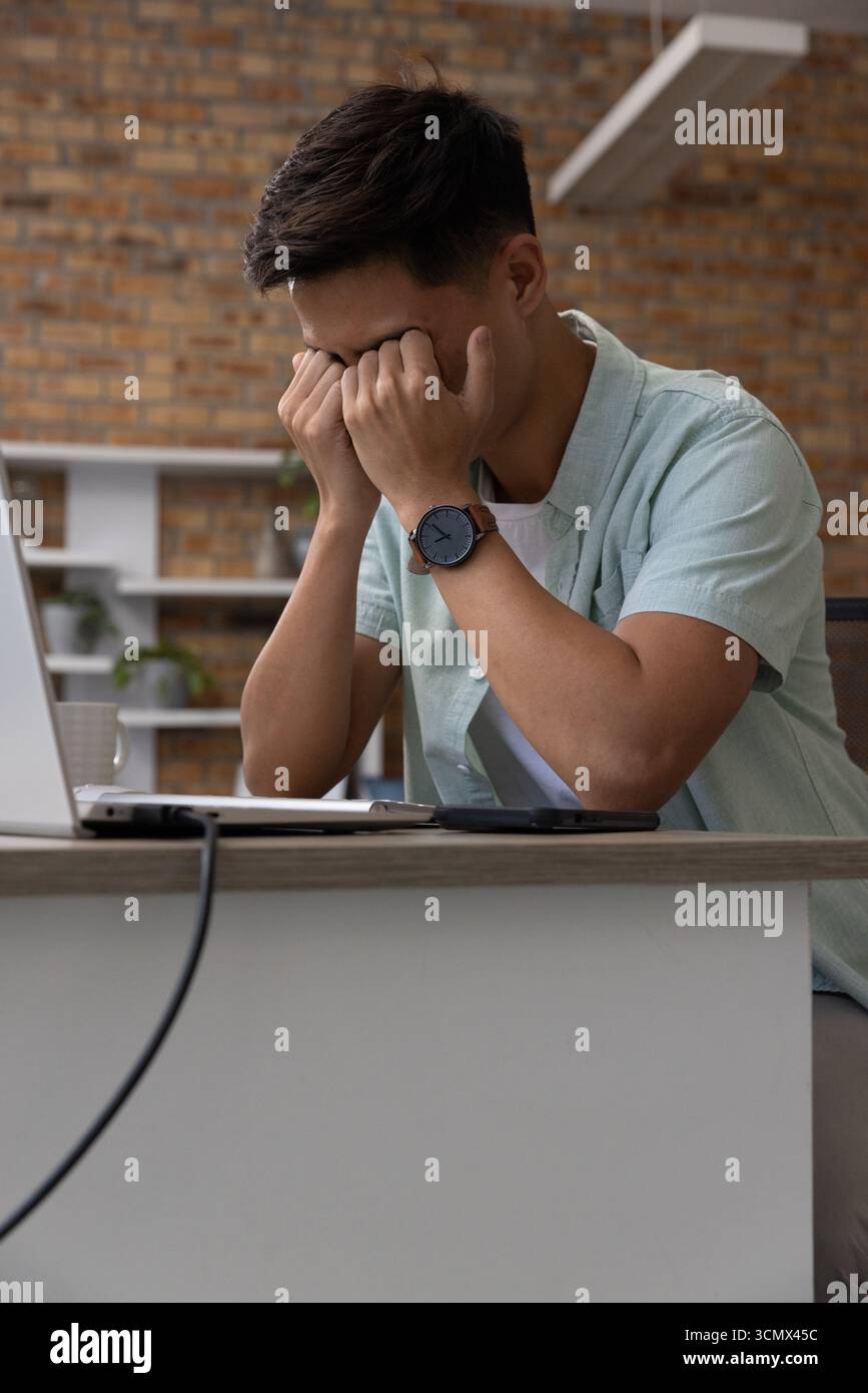 Silberner Laptop, der im Büro auf dem Schreibtisch sitzt, mit Kaffeetasse, Smartphone und Ladekabel Stockfoto