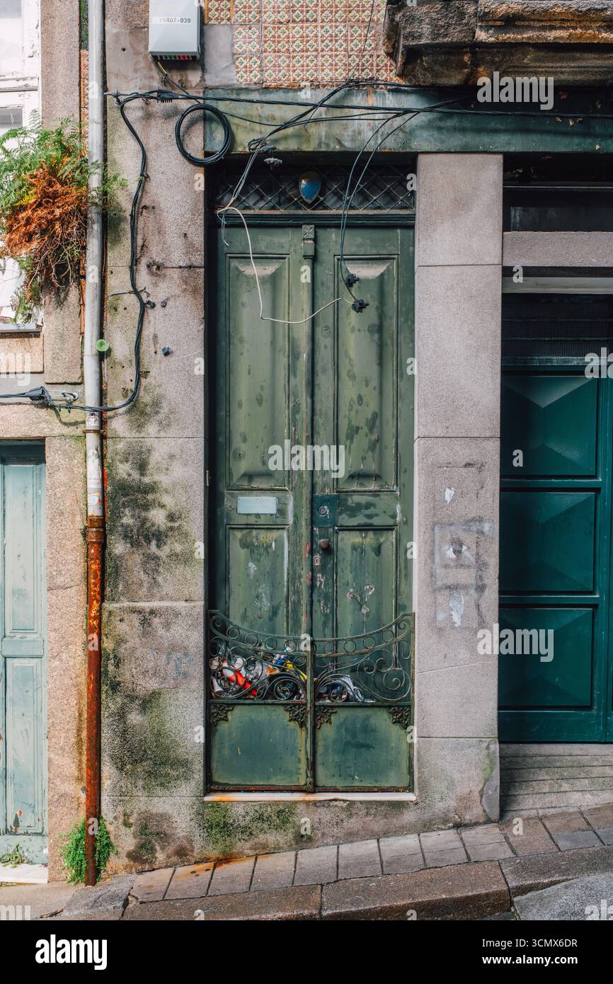 Holztür mit geometrischen Schnitzereien und Schachbrettfliesen in Porto. Steinbogen mit Scrollwerk, blauen Keramikmustern, kulturelles Handwerk Stockfoto