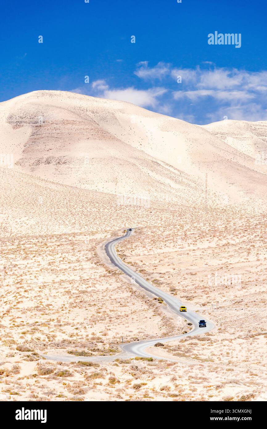 Blick auf Autos, die auf einer gewundenen Wüstenstraße in der kargen Landschaft fahren, Jandia, Fuerteventura, Kanarischen Inseln, Spanien Stockfoto