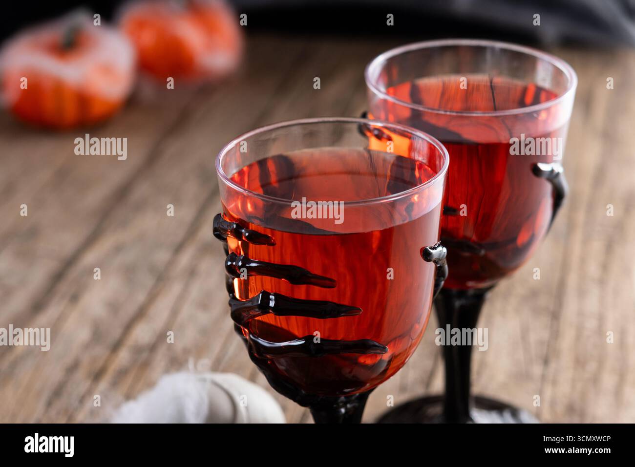 Halloween gruseliger roter Cocktail in Skelett Handglas auf schwarzem Hintergrund Stockfoto