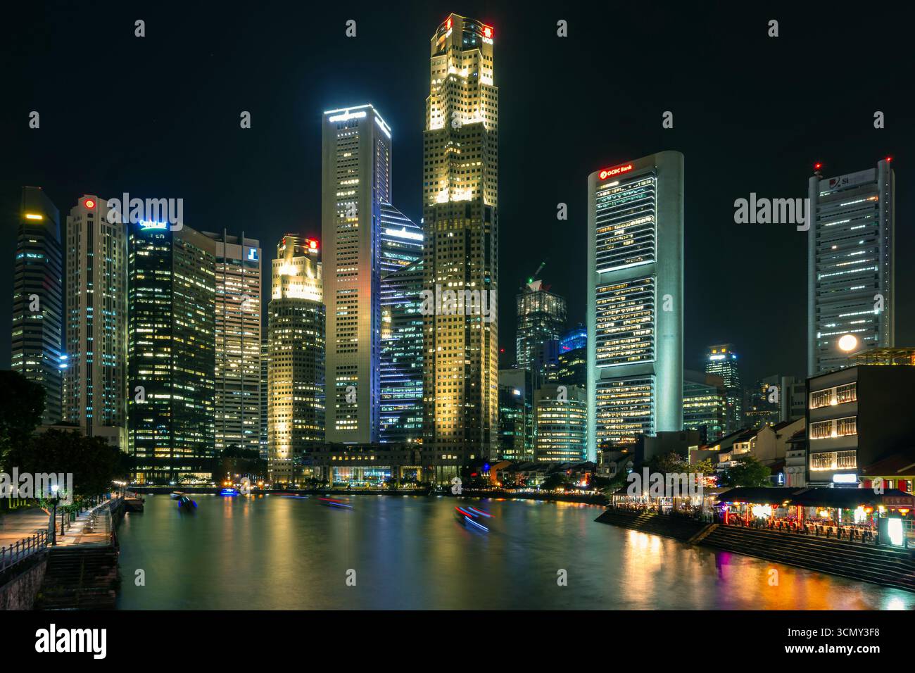 singapur - raffles Place at Night - lange Exposition mit wunderschönen Lichtstreifen und Reflexionen von der beleuchteten Skyline im Wasser Stockfoto