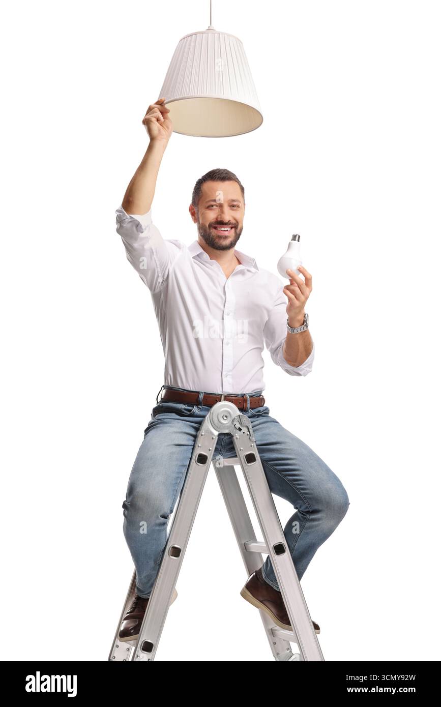Mann, der eine Glühbirne für eine Pendelleuchte hält und auf einer Leiter sitzt, isoliert auf weißem Hintergrund Stockfoto