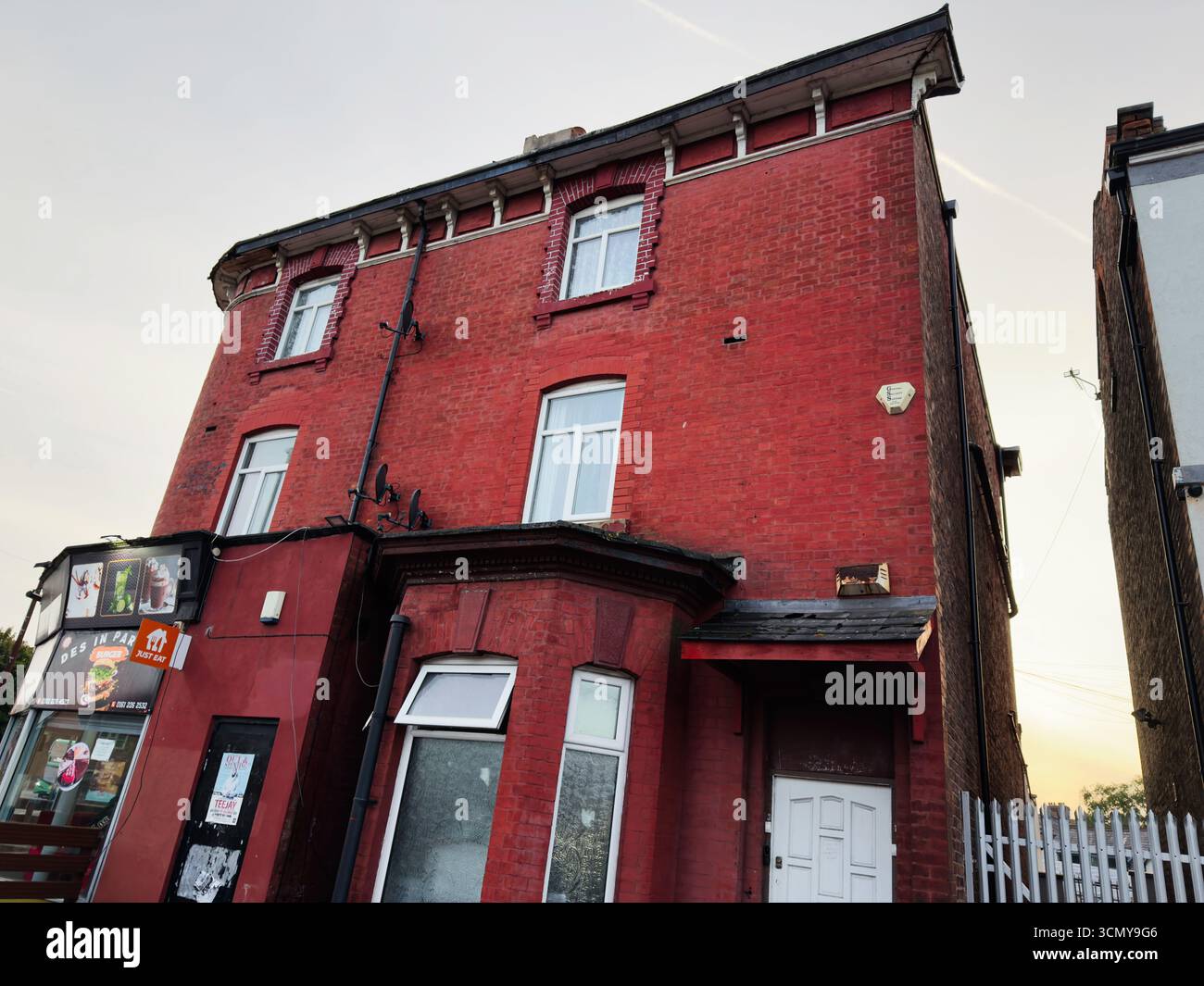 Manchester, Großbritannien - 16. September 2025: Historisches rotes Backsteingebäude mit Ladenfront in Manchester, Großbritannien. Stockfoto