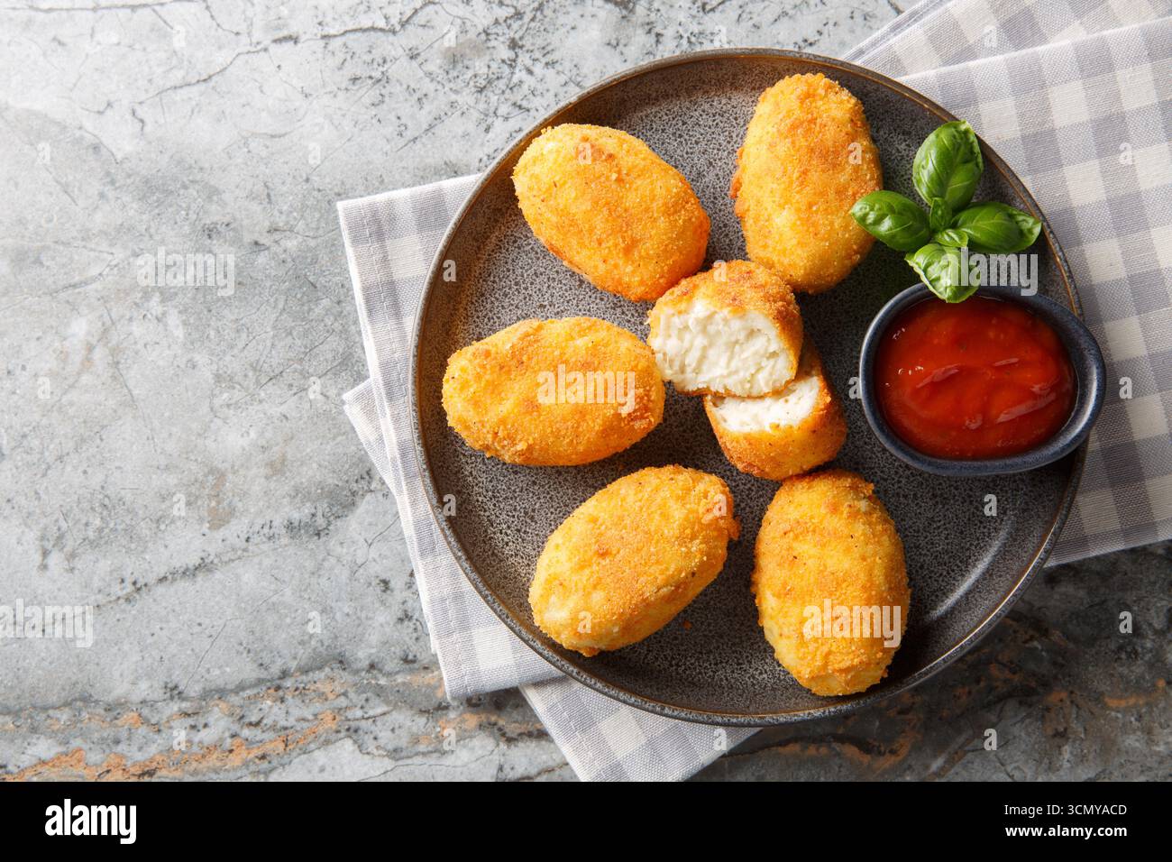 Köstliche knusprige panierte Hähnchenkroketten, serviert mit Tomatensauce in Nahaufnahme auf einem Teller auf dem Tisch. Horizontale Draufsicht von oben Stockfoto