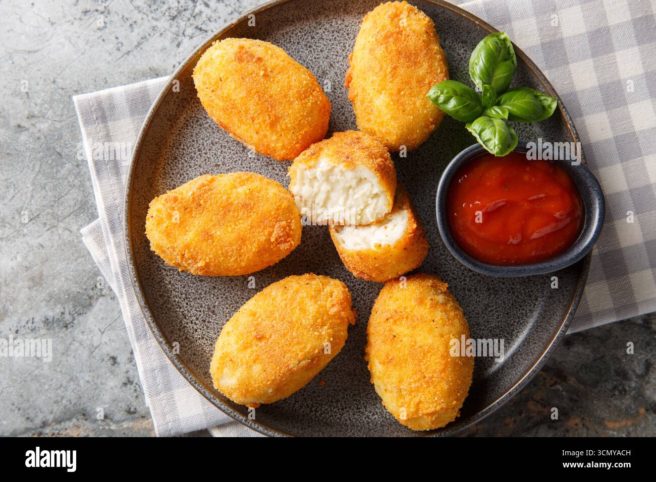 Heiße Hähnchenbechamelkroketten mit Ketchup in Nahaufnahme auf einem Teller auf dem Tisch. Horizontale Draufsicht von oben Stockfoto