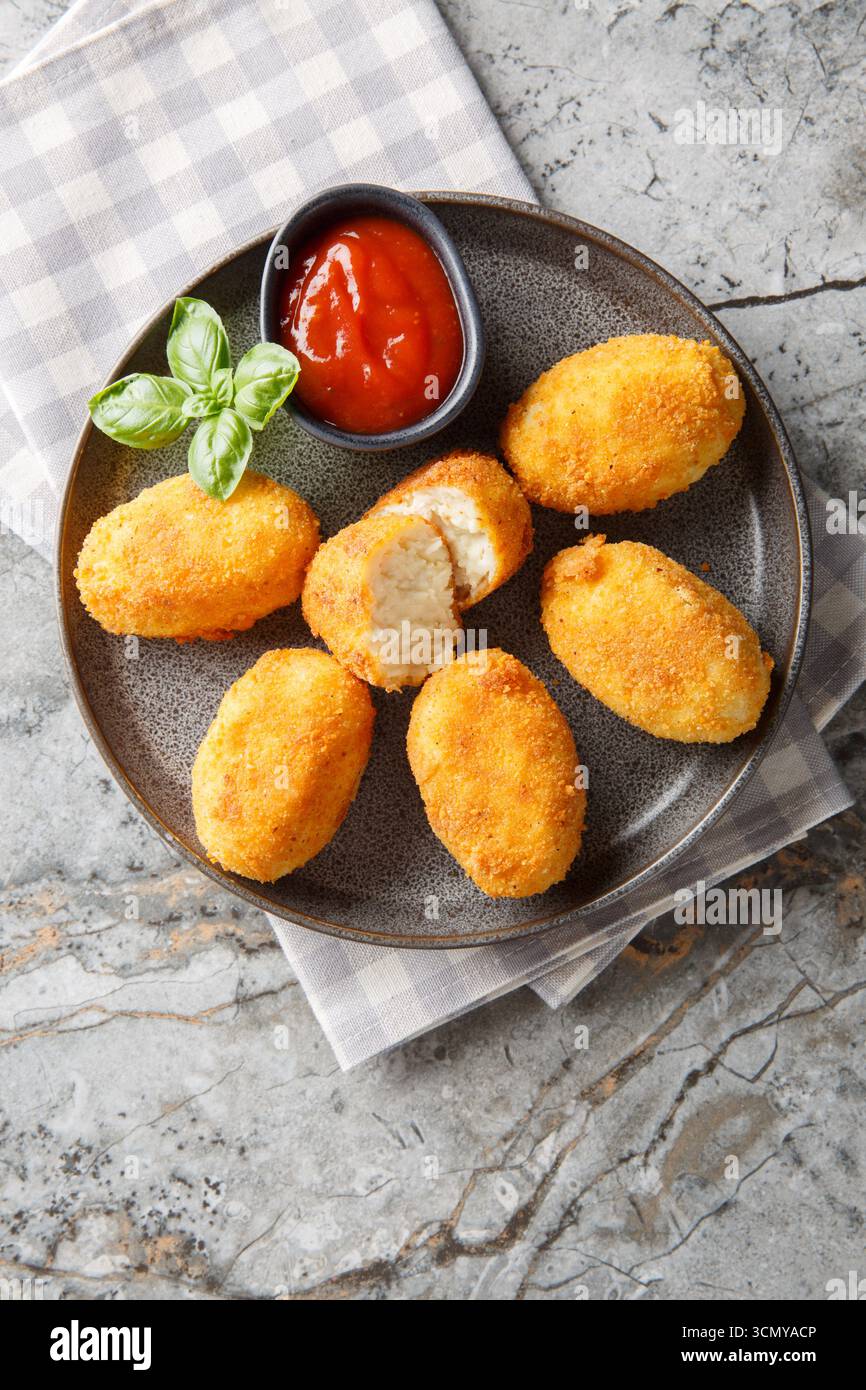 Spanische Croquettes Hühnchen in einer cremigen Bechamelsauce serviert mit Tomatensoße in Nahaufnahme auf einem Teller auf dem Tisch. Vertikale Draufsicht von oben Stockfoto