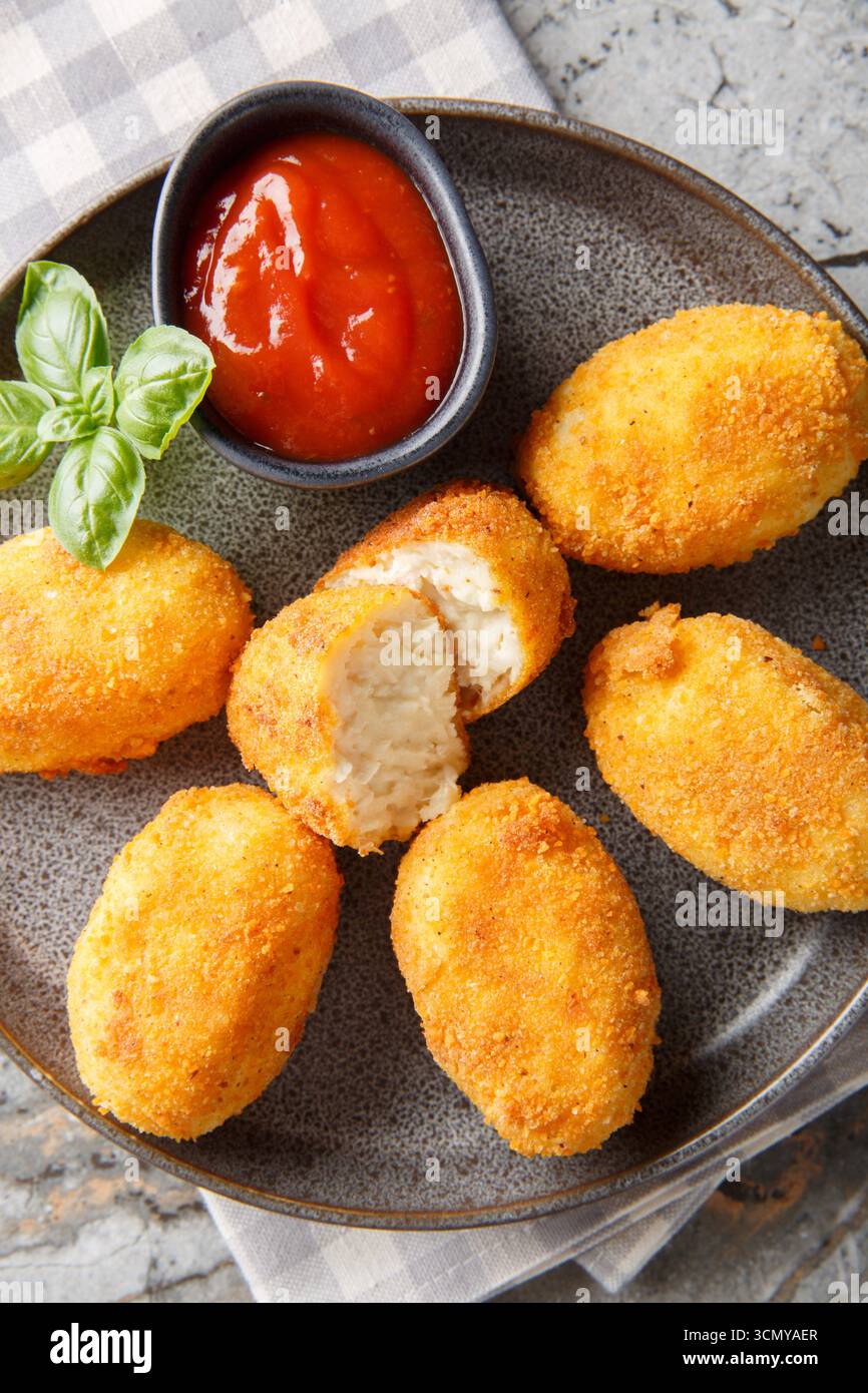 Nahaufnahme von spanischen Hähnchenkroketten mit Ketchup auf einem Teller auf einem Tisch. Vertikale Draufsicht von oben Stockfoto