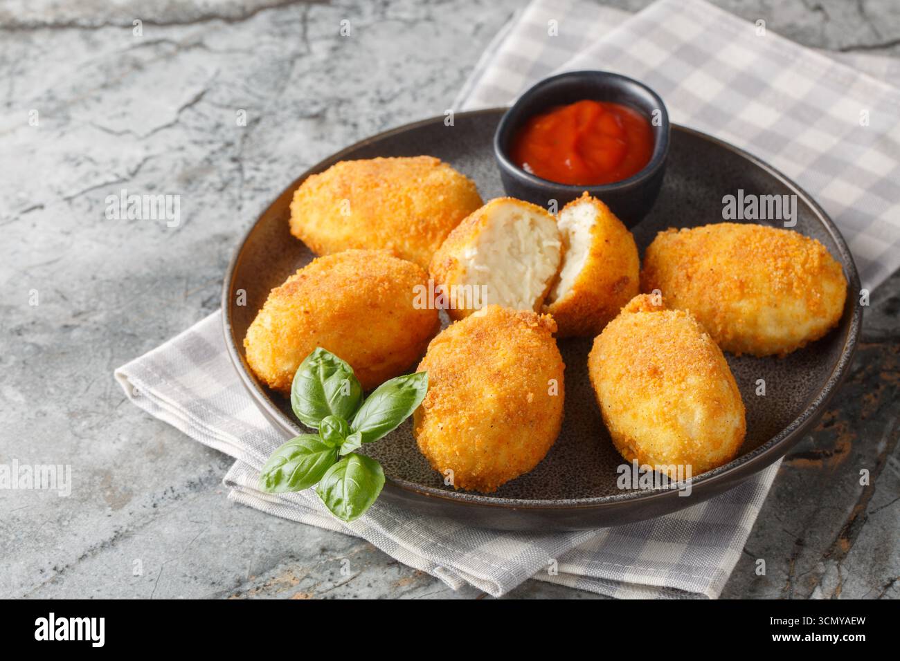 Köstliche knusprige panierte Hähnchenkroketten, serviert mit Tomatensauce in Nahaufnahme auf einem Teller auf dem Tisch. Horizontal Stockfoto