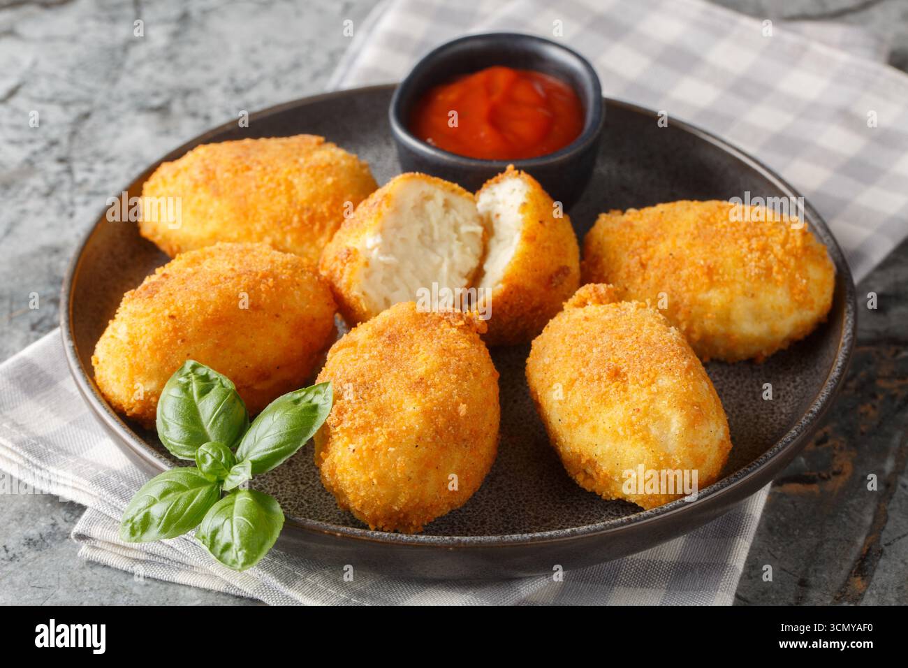 Heiße Hähnchenbechamelkroketten mit Ketchup in Nahaufnahme auf einem Teller auf dem Tisch. Horizontal Stockfoto