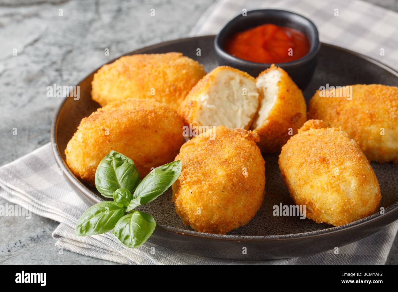 Panierte und frittierte Hähnchenkroketten serviert Tomatensauce in Nahaufnahme auf einem Teller auf dem Tisch. Horizontal Stockfoto