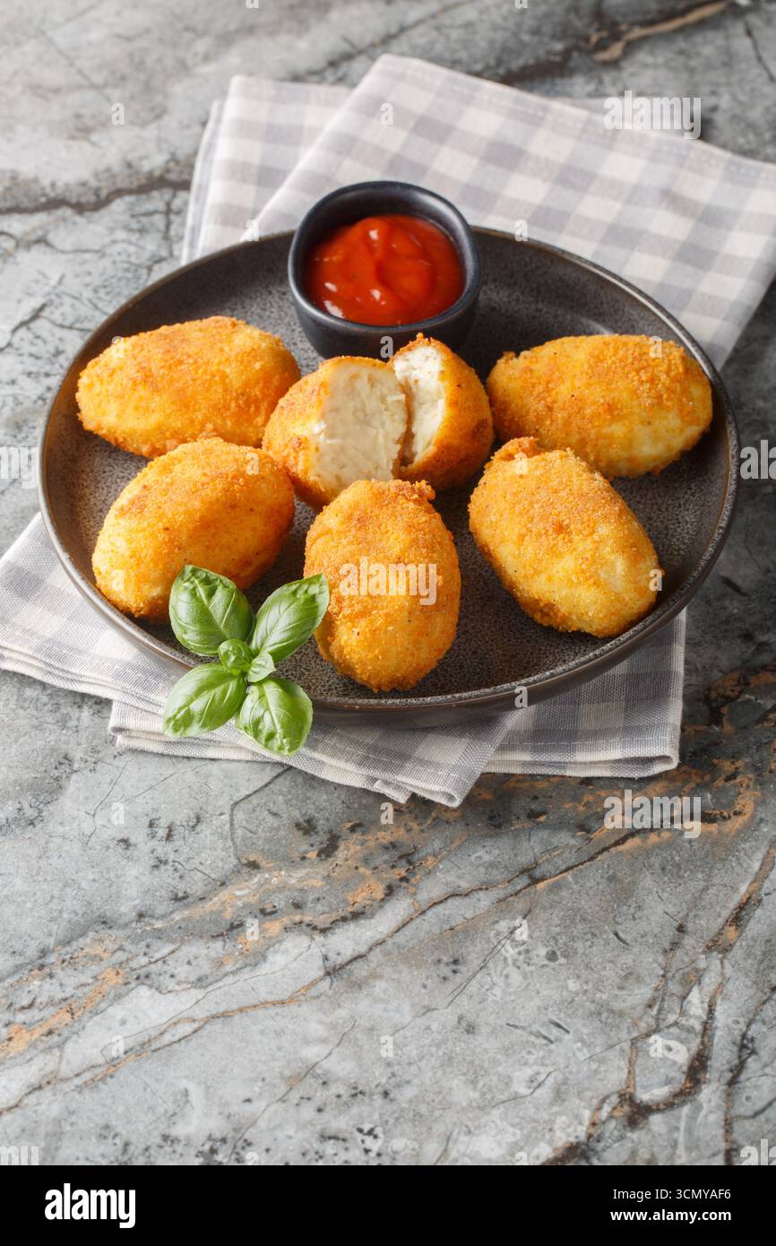 Nahaufnahme von spanischen Hähnchenkroketten mit Ketchup auf einem Teller auf einem Tisch. Vertikal Stockfoto