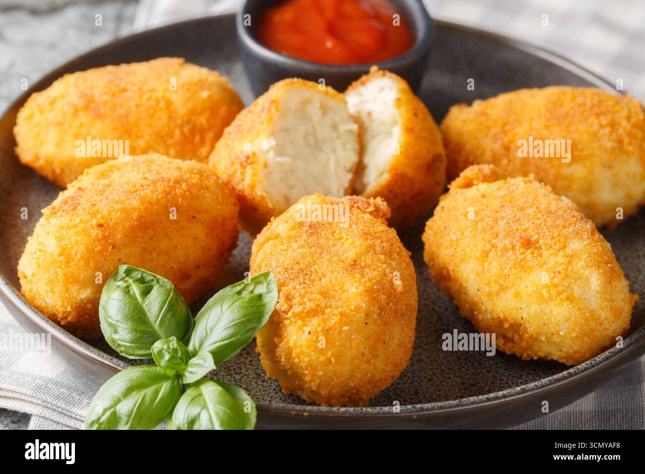 Spanische Croquettes Hühnchen in einer cremigen Bechamelsauce serviert mit Tomatensoße in Nahaufnahme auf einem Teller auf dem Tisch. Horizontal Stockfoto