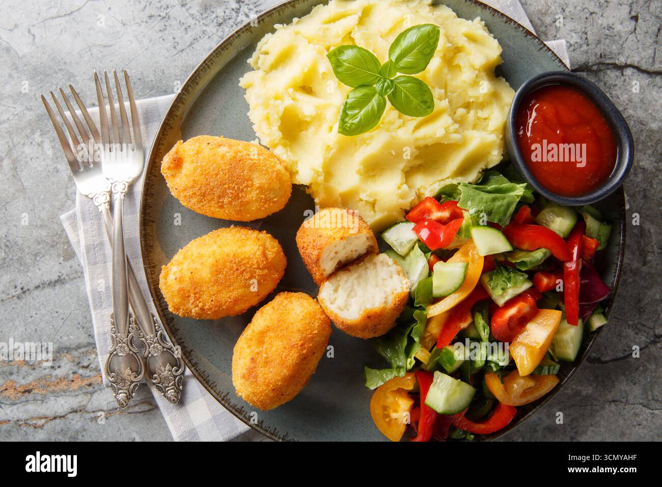 Spanische Croquettes Hühnchen in einer cremigen Bechamelsauce serviert mit Kartoffelpüree, frischem Salat und Tomatensauce in Nahaufnahme auf einem Teller auf dem Tisch. Hori Stockfoto