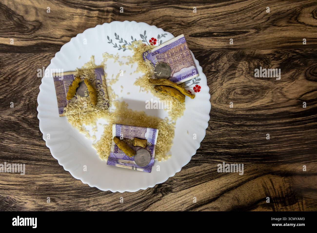 Teller mit Geld, roher haldi und Reis, so genannte hinduistische Rituale shagun in indischen Traditionen im Innenbereich Stockfoto