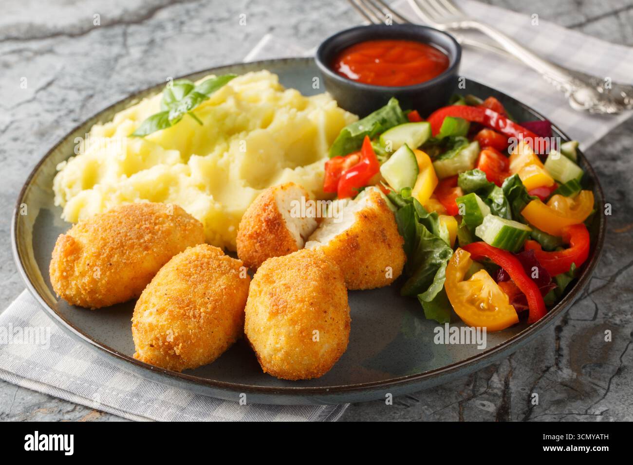 Spanische Croquettes Hühnchen in einer cremigen Bechamelsauce serviert mit Kartoffelpüree, frischem Salat und Tomatensauce in Nahaufnahme auf einem Teller auf dem Tisch. Hori Stockfoto