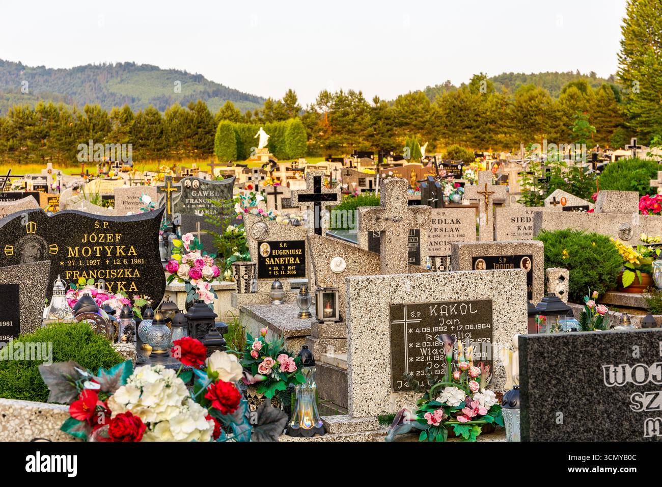 Milowka, Polen, 08.07.2021. Friedhof mit traditionellen Granitgräbern, dekoriert mit bunten künstlichen Blumen und Kerzen in den Beskid Mountains. Stockfoto