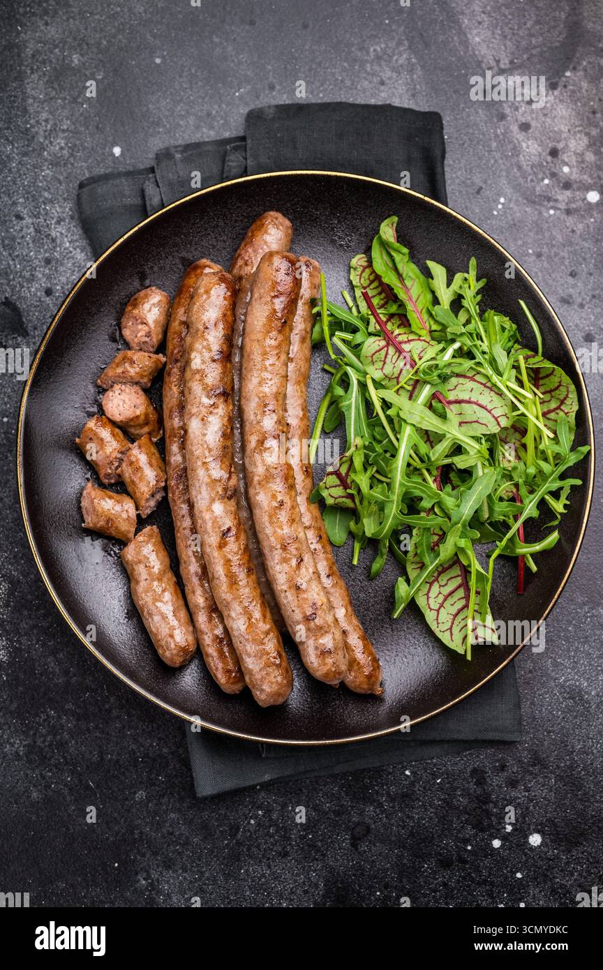 Rauchige gegrillte Wurst mit Grillmarkierungen, perfekt für die Erfüllung von Heißhunger bei Grillveranstaltungen und zwanglosen Dining-Events. Schwarzer Hintergrund. Draufsicht. Stockfoto
