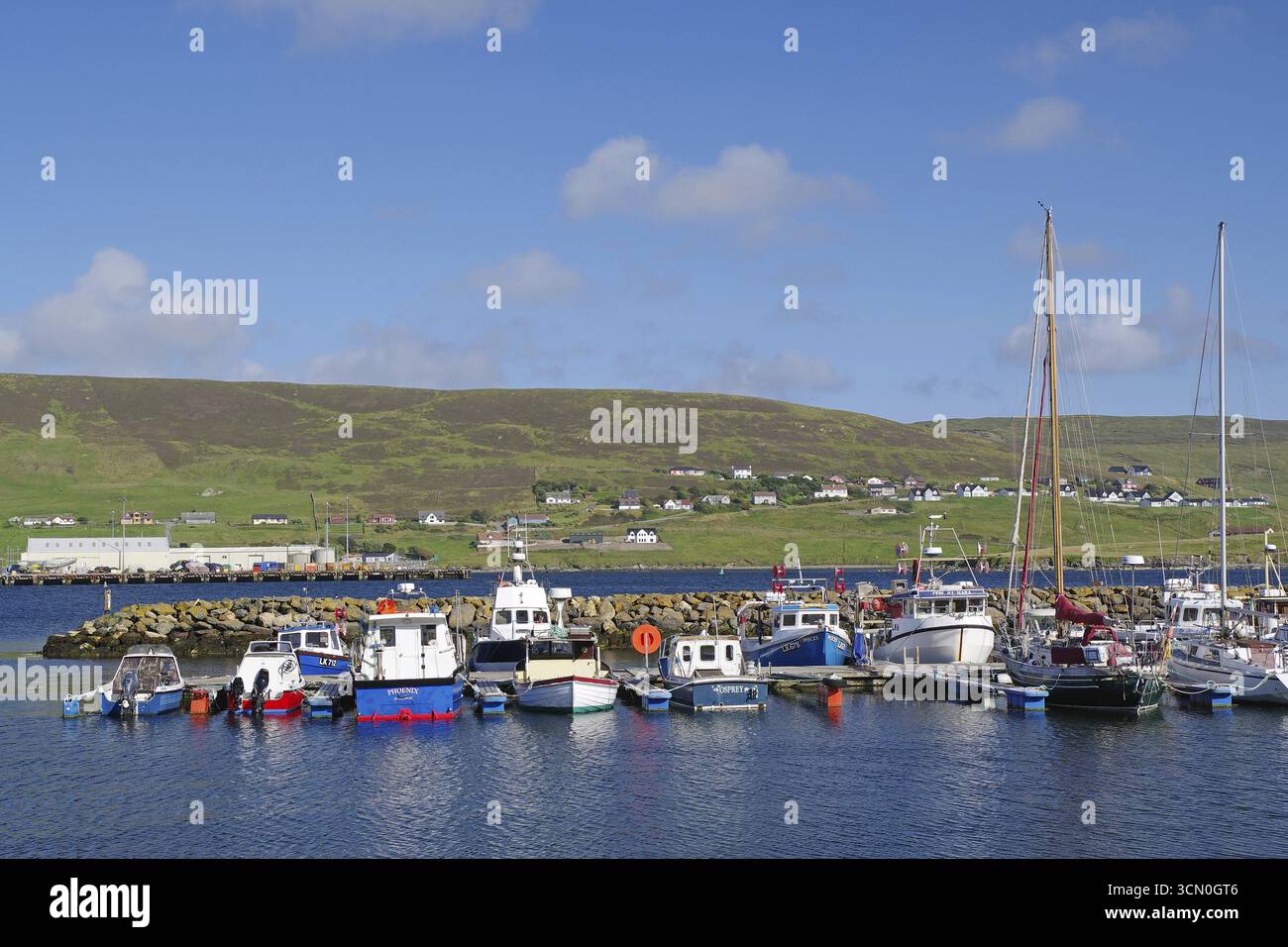 Ein ruhiger Hafen mit Booten und grünen Hügeln im Hintergrund, Scalloway, Shetland Islands, Schottland, Großbritannien Stockfoto