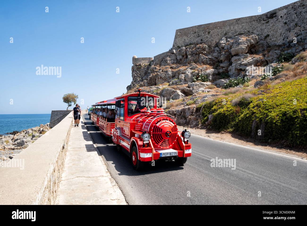 Rethymno, Kreta, Griechenland. Die Stadtrundfahrt mit Audioguide, gefüllt mit Touristen, fährt entlang der Küstenstraße, vorbei am Schloss Fortezza Stockfoto