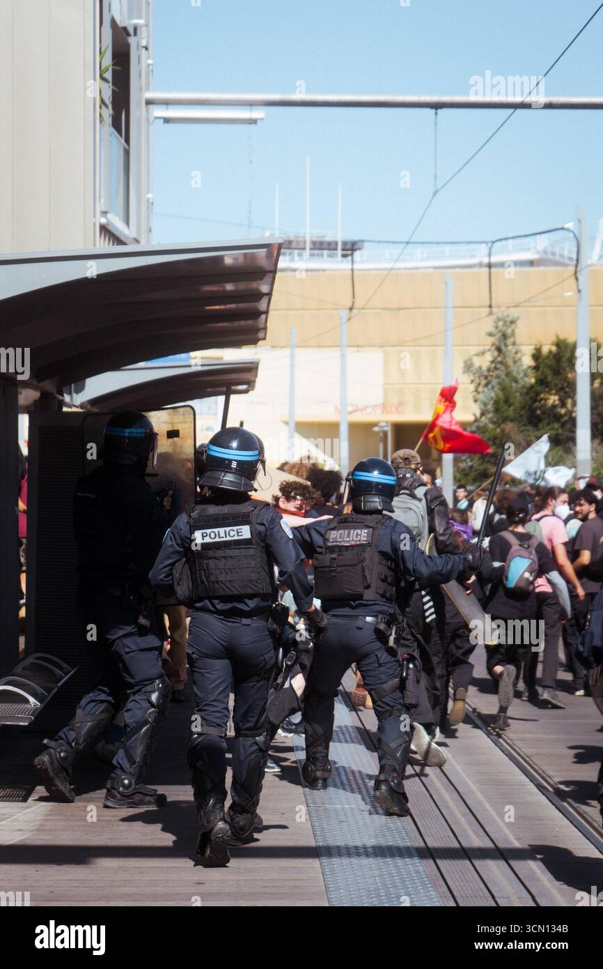 Policier frappant un manifestant avec sa matraque à l'arrêt de Tramway ligne 1 du Guesclin Stockfoto