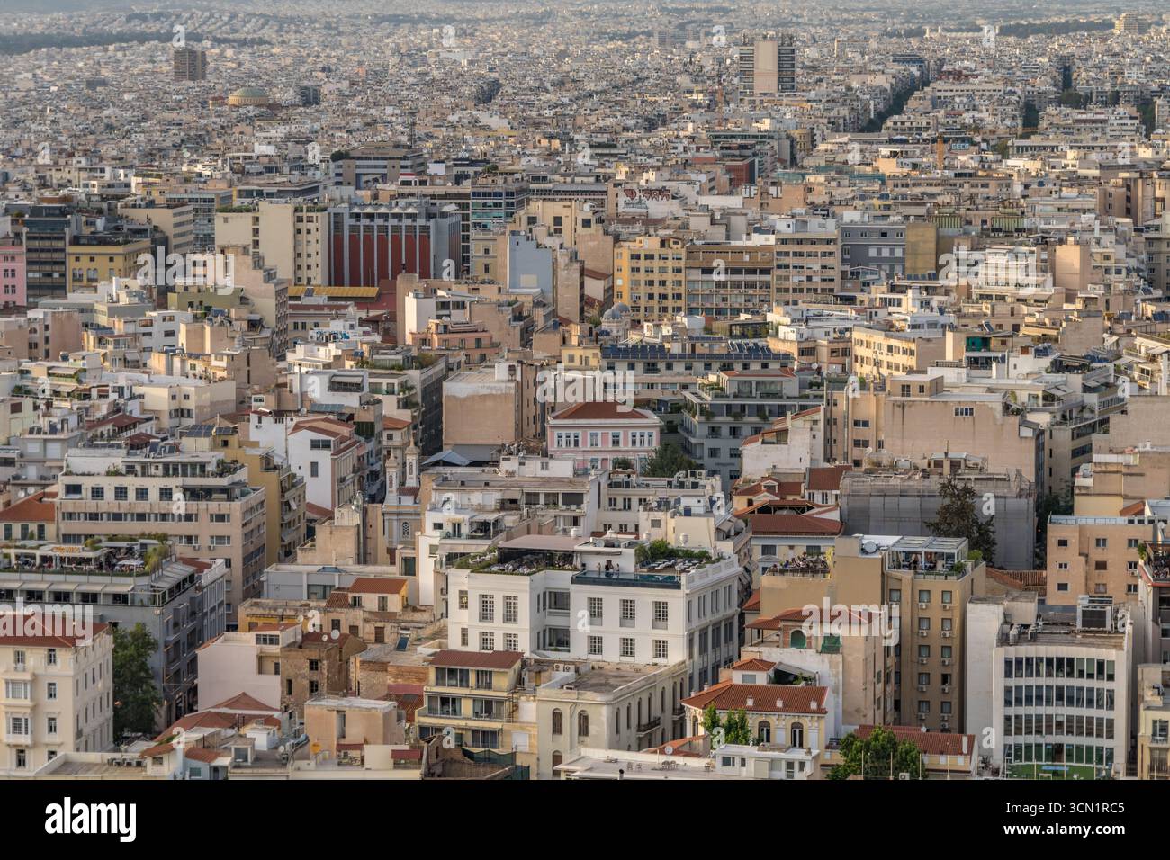 Breiter Panoramablick über das Zentrum von Athen mit einer dichten Verteilung von Dächern und mittelhohen Gebäuden, die sich bis zum fernen Horizont, Griechenland, erstrecken. Mai 2025 Stockfoto