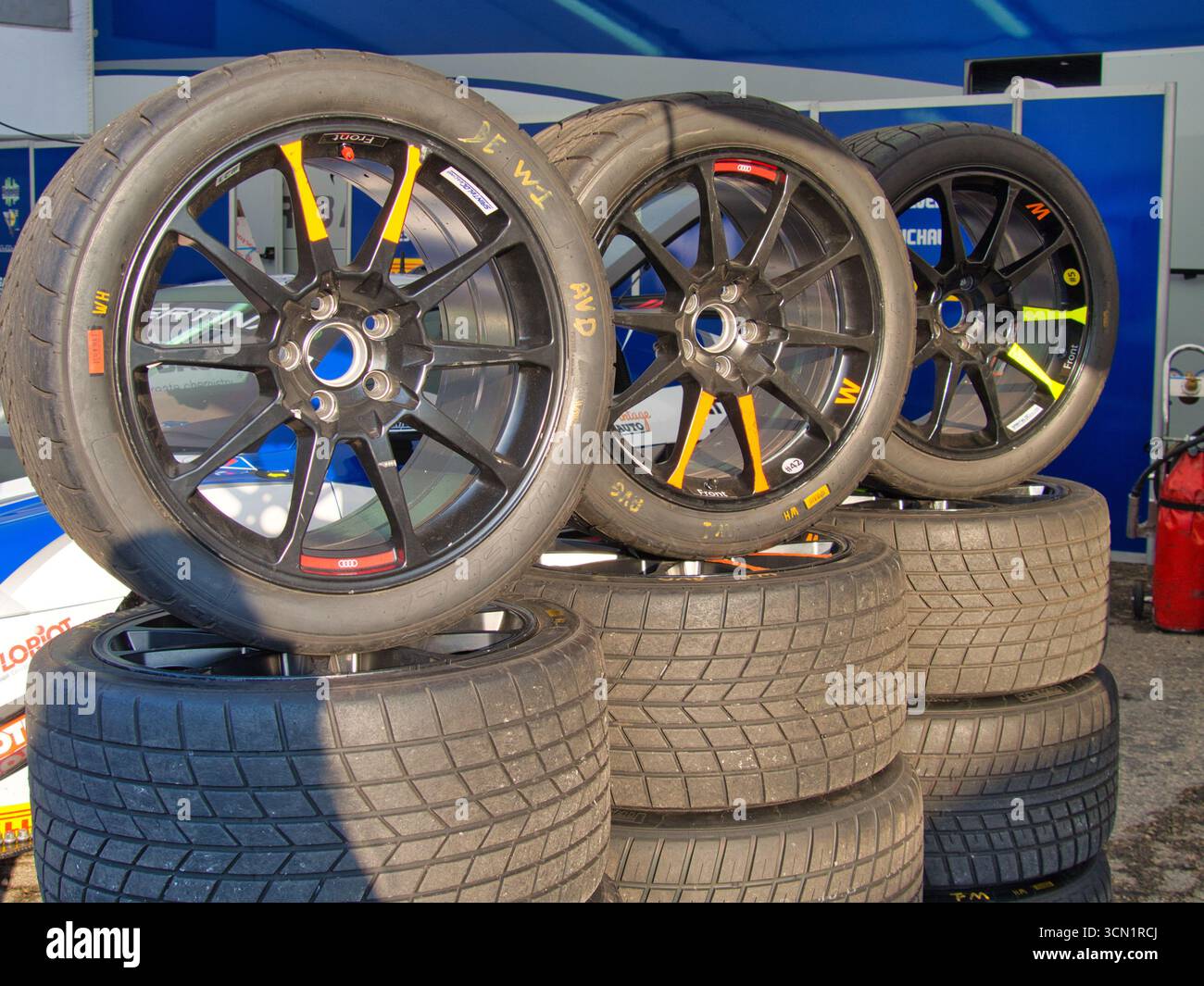 Stack der High-Performance Racing Reifen – Eine detaillierte Aufnahme von gestapelten Slick-Reifen und Felgen, die für ein Rennen bereit sind, symbolisiert Geschwindigkeit, Technologie und Team Pre Stockfoto