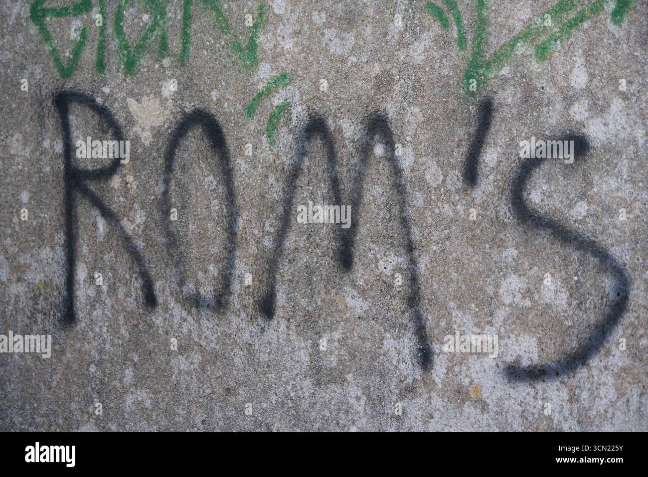 Graffiti auf Betonwand mit Black Tag über Green Street Art und verwitterter Textur. Bonifacio, Korsika, Frankreich Stockfoto