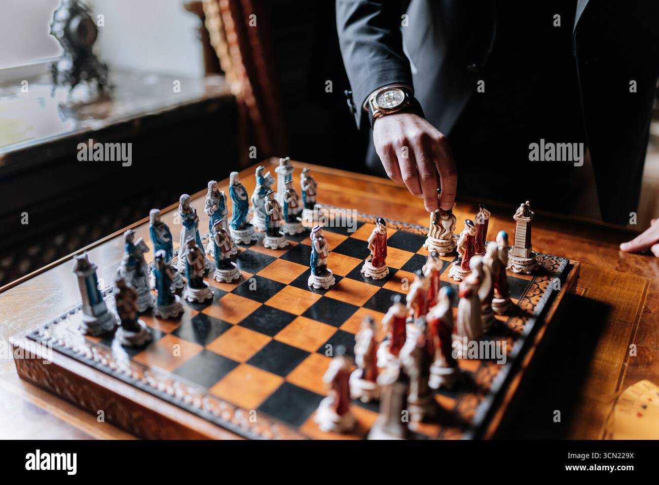 Geschäftsmann macht strategischen Schritt mit Vintage-Schachfiguren auf Luxusbrettern Stockfoto
