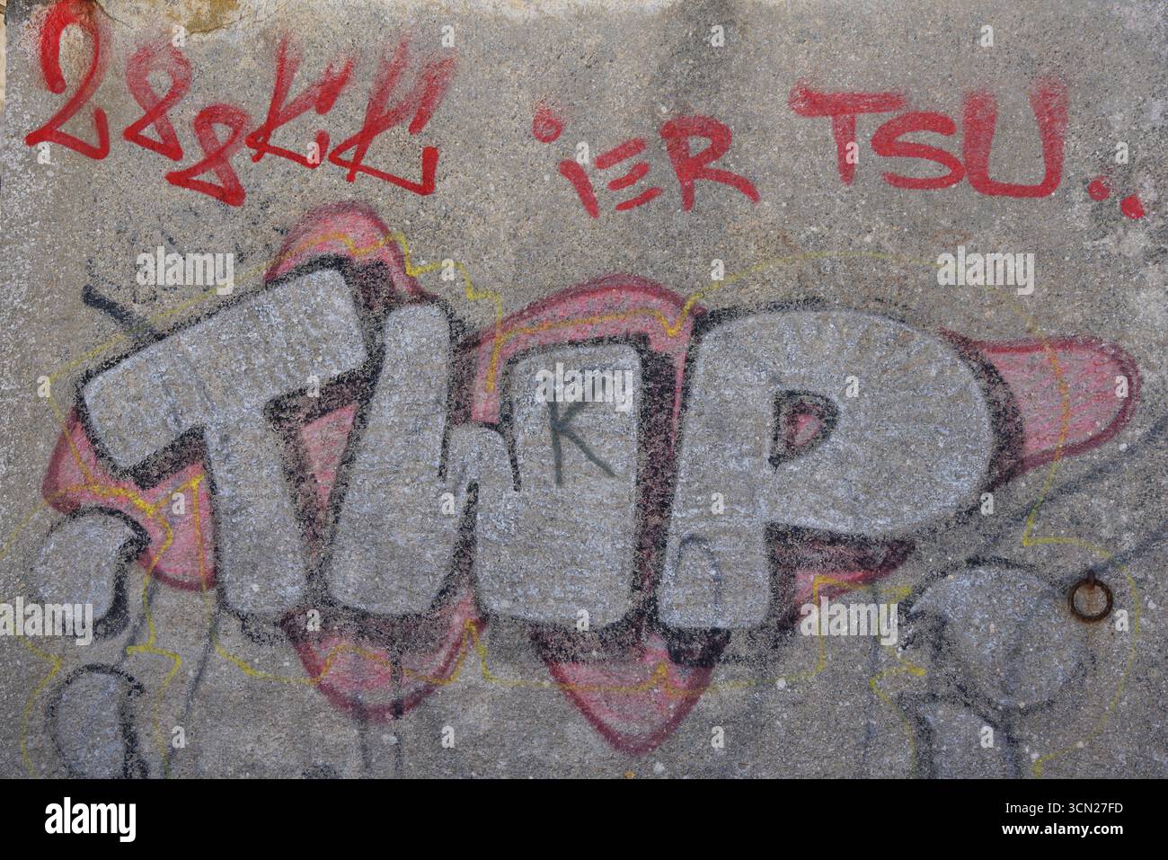 Graffiti-Buchstaben auf Betonwand mit rotem Tagging und weichem grauem Hintergrund. Bonifacio, Korsika, Frankreich Stockfoto