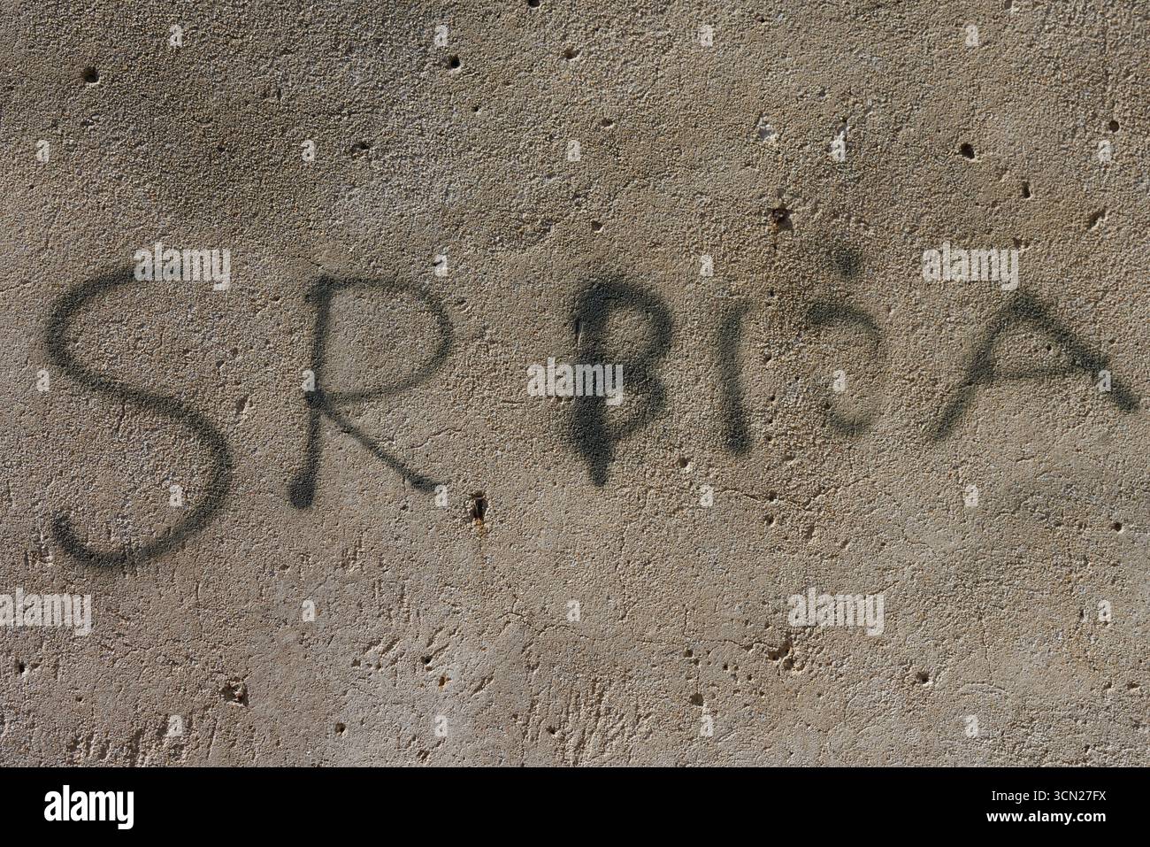Graffiti auf verwitterter Wand gibt SRBNA mit Bold Black Sprühfarbe, Urban Texture, Beton wieder. Bonifacio, Korsika, Frankreich Stockfoto