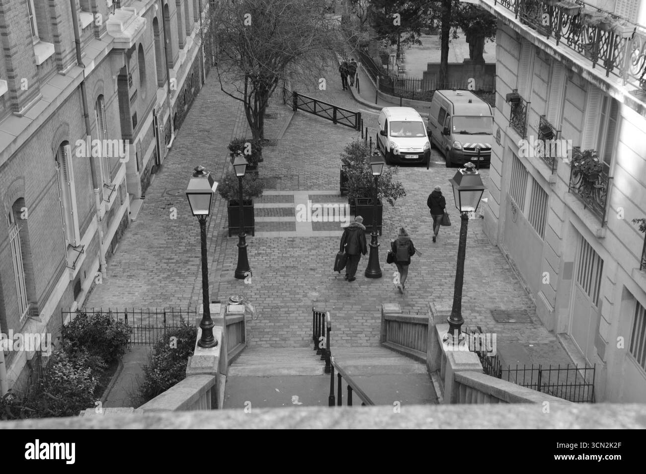 Kopfsteinpflasterstraße und Treppe in Montmartre, Paris, Frankreich, mit Leuten, die an einem Wintertag im Januar spazieren gehen. Klassische Pariser Architektur. Stockfoto