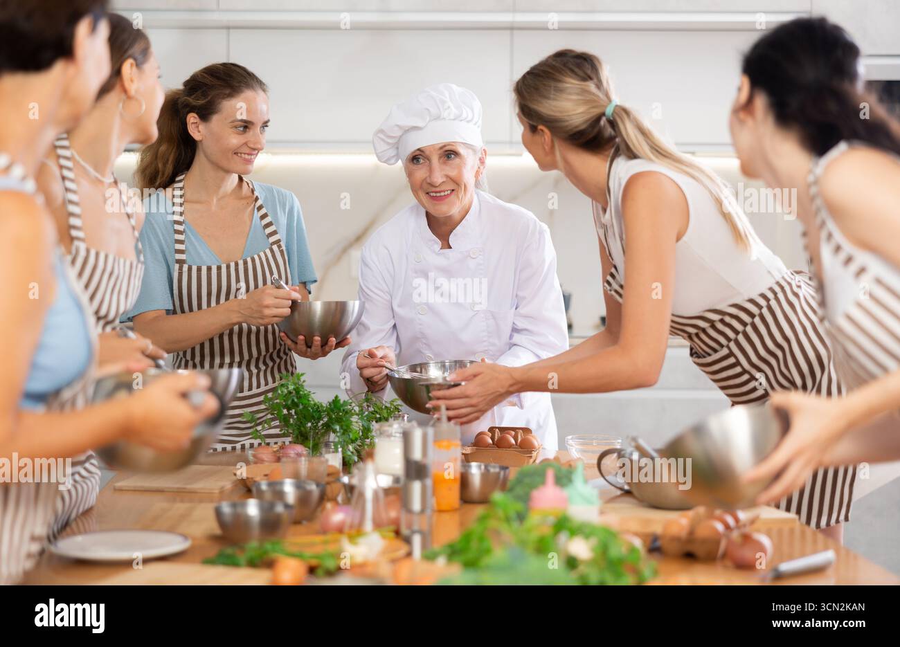Reife weibliche Köchin mit Schüssel und Schneebesen Stockfoto